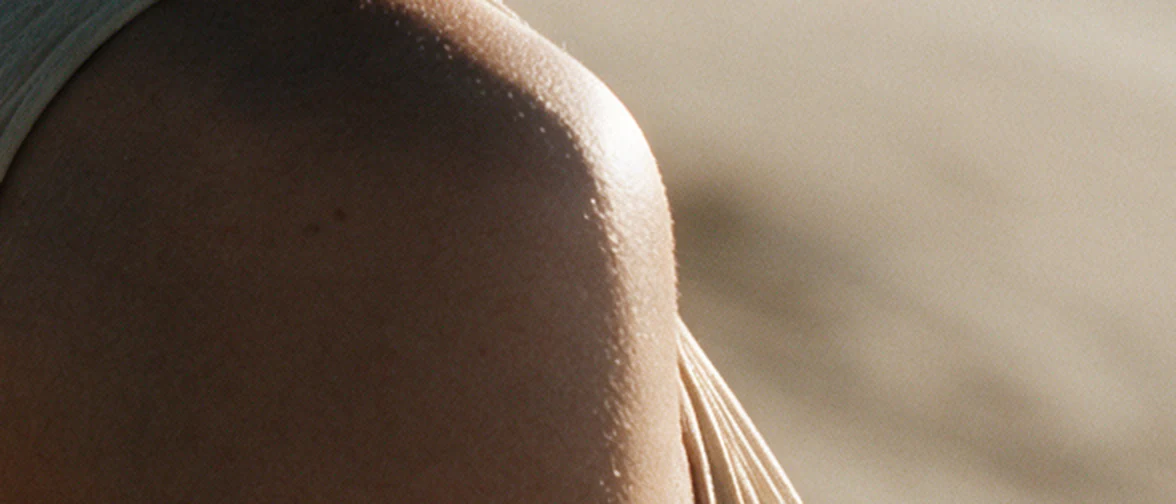 Close-up of a bare shoulder in warm sunlight, nothing on the skin.